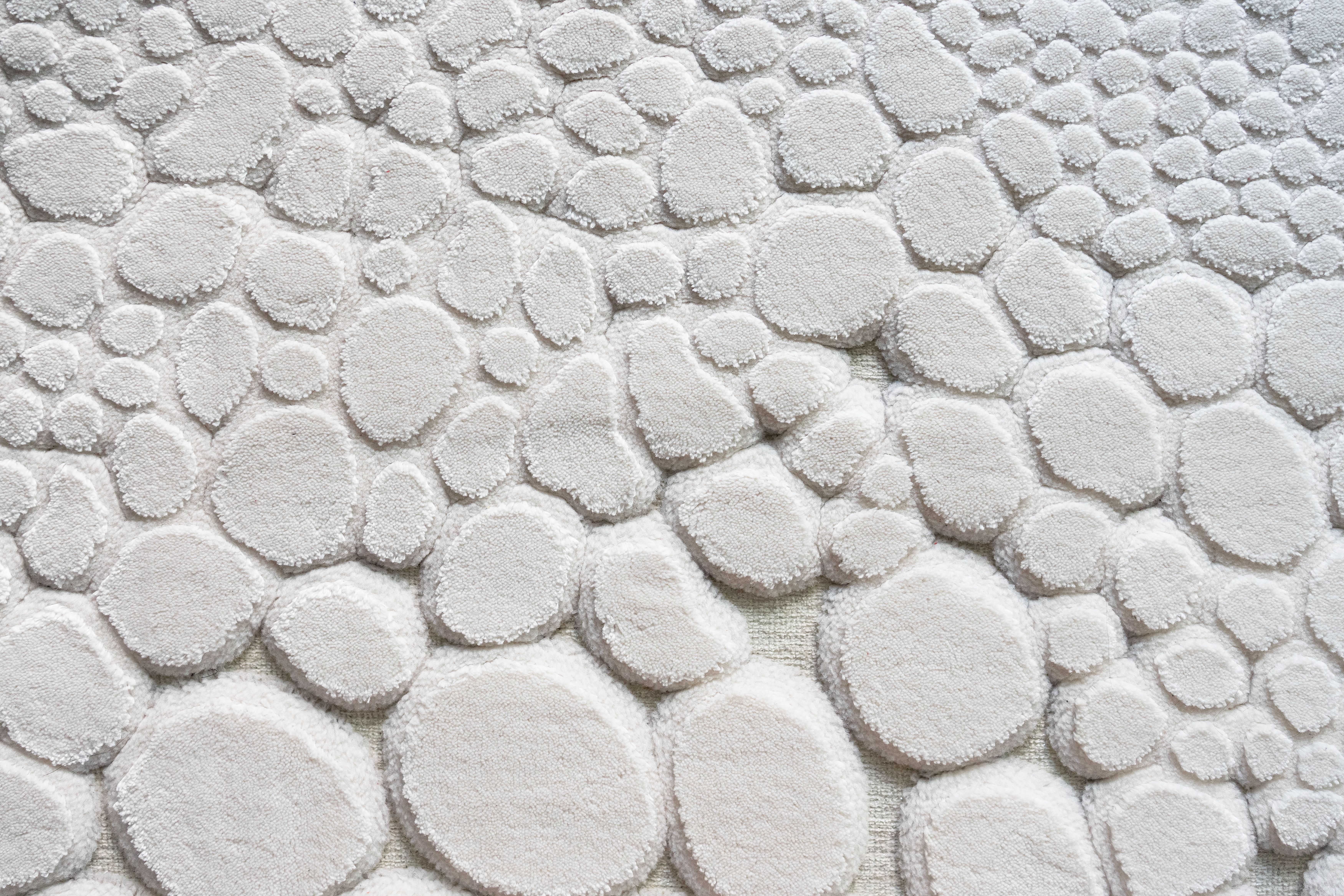 A white wall with a pattern of white pebbles · Free Stock Photo
