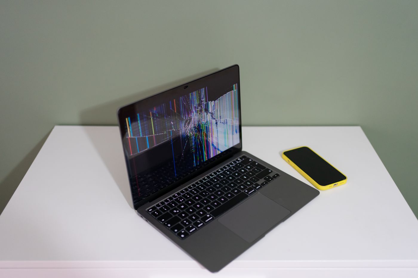 Laptop with a cracked screen next to a phone