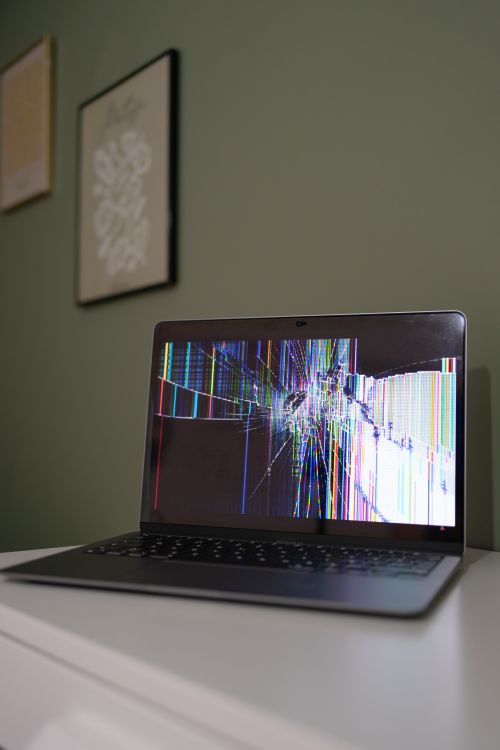 A laptop with a broken screen sitting on a table · Free Stock Photo
