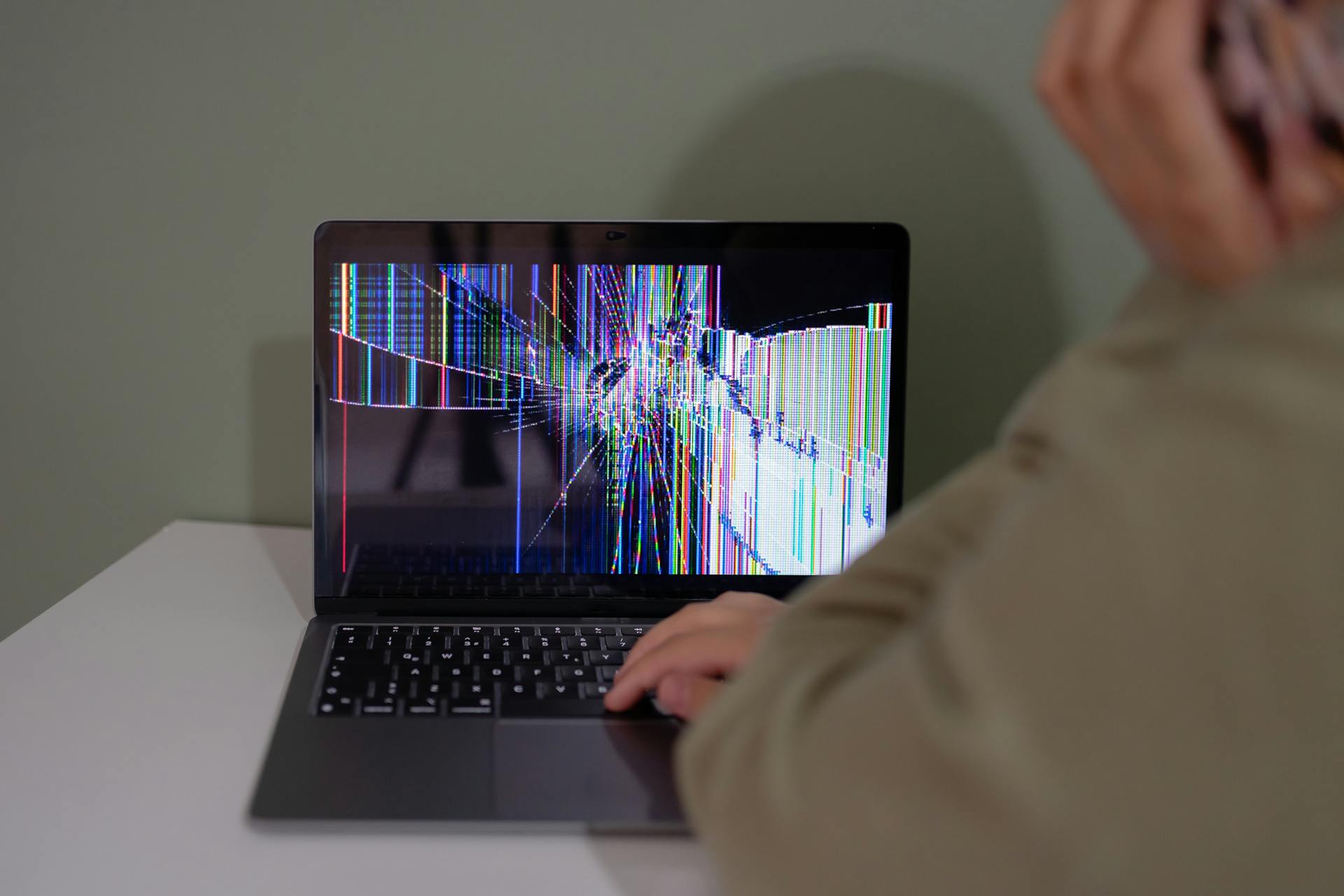 A person is using a laptop with a broken screen