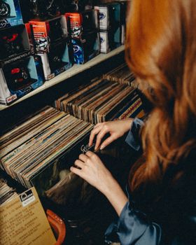 Woman looking through vinyl records in a vintage Maringá store, capturing nostalgic vibes.