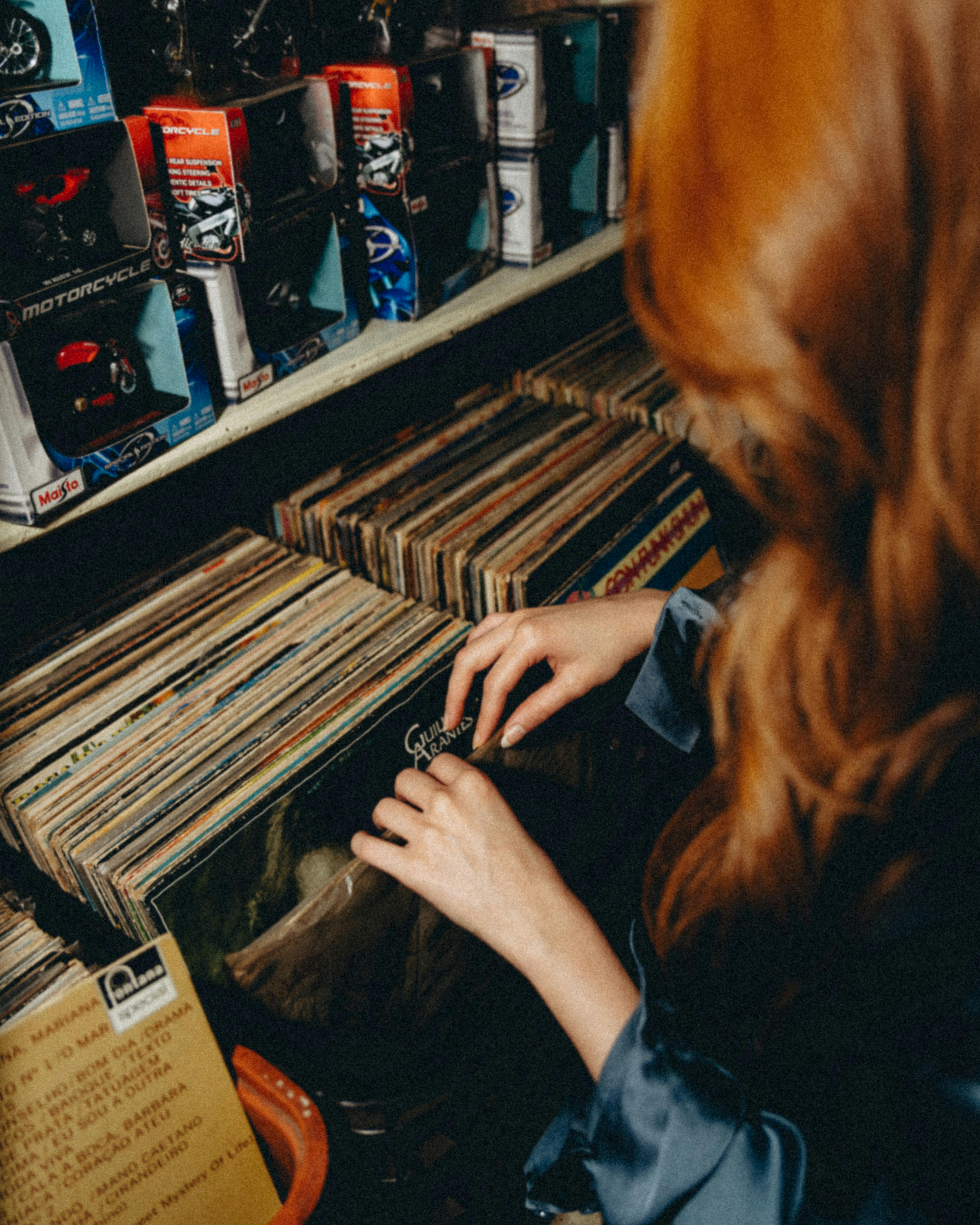 gratis Een vrouw bladert door vinylplaten in een vintage winkel in Maringá en haalt nostalgische gevoelens op. Stockfoto