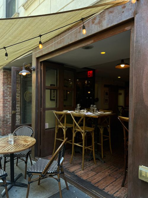 Free Inviting outdoor cafe with elegant table and chairs, leading into a warmly lit interior. Stock Photo