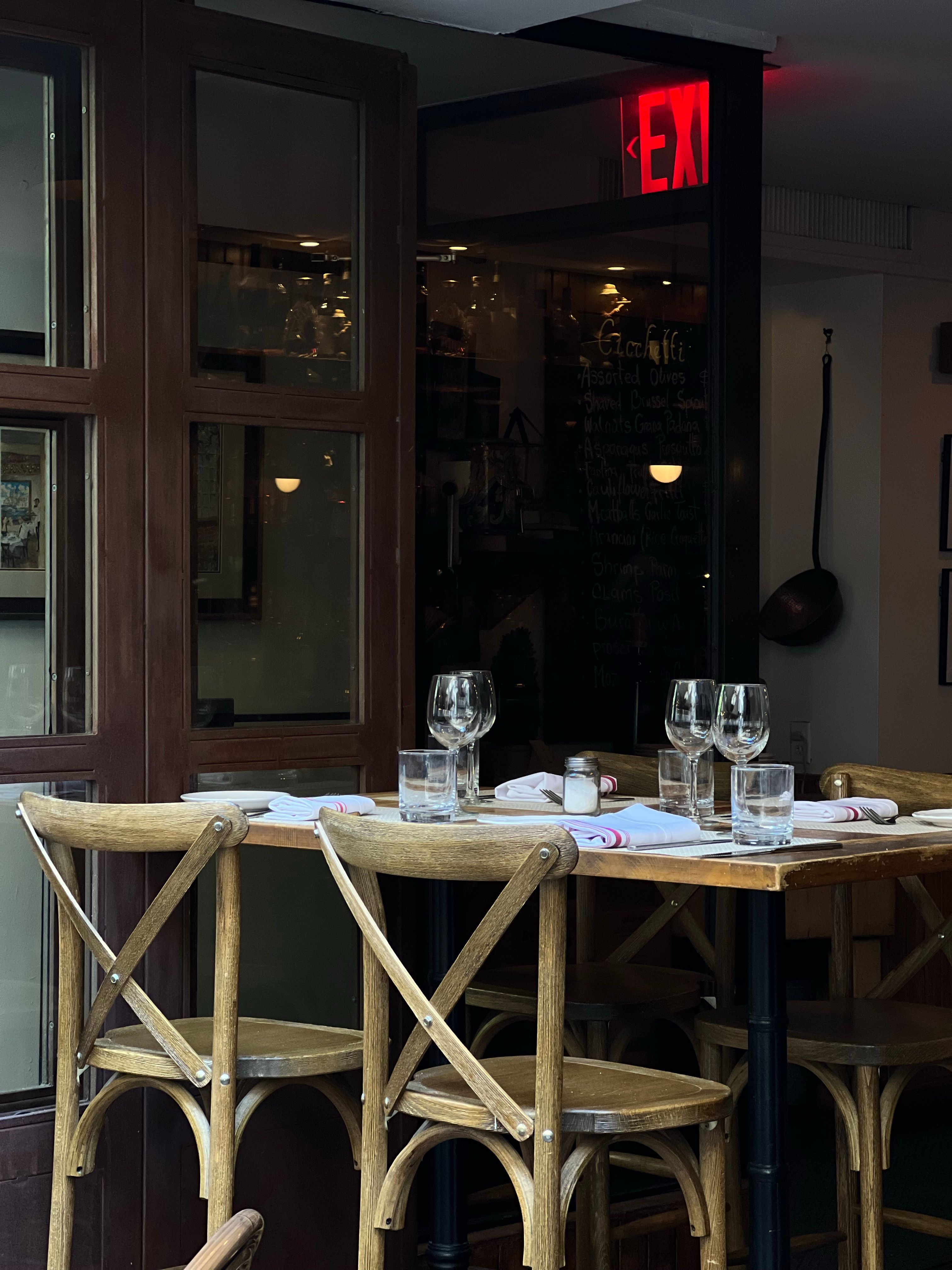 Inviting restaurant table set for four with wine glasses and napkins under warm lighting.
