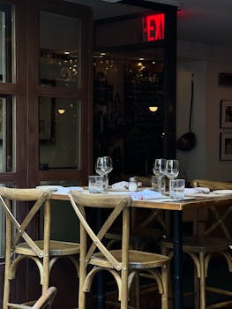 A rustic café table set for dining, capturing a cozy ambiance with wooden chairs and glassware.