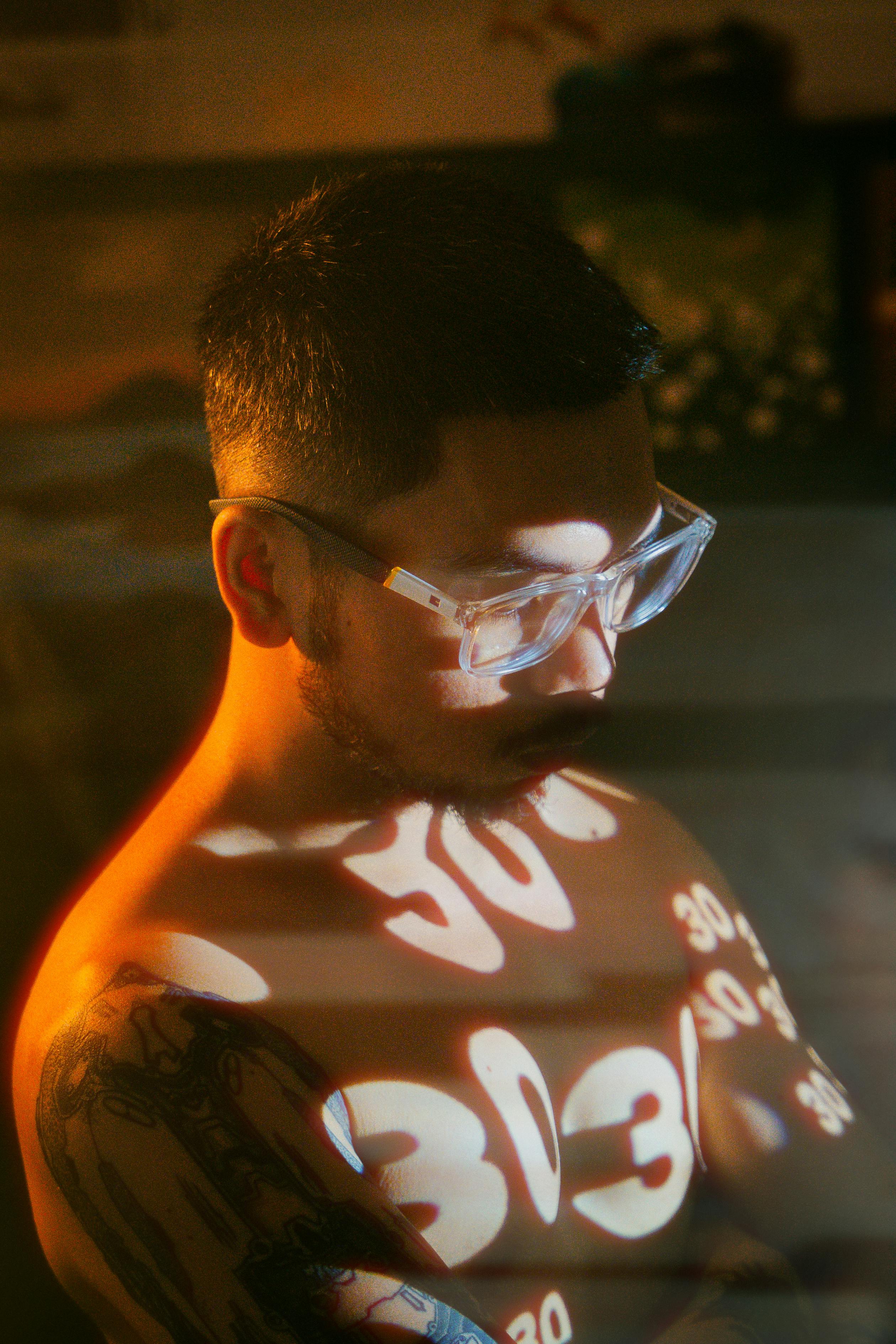 Portrait of a man with light reflections creating artistic patterns on his skin.