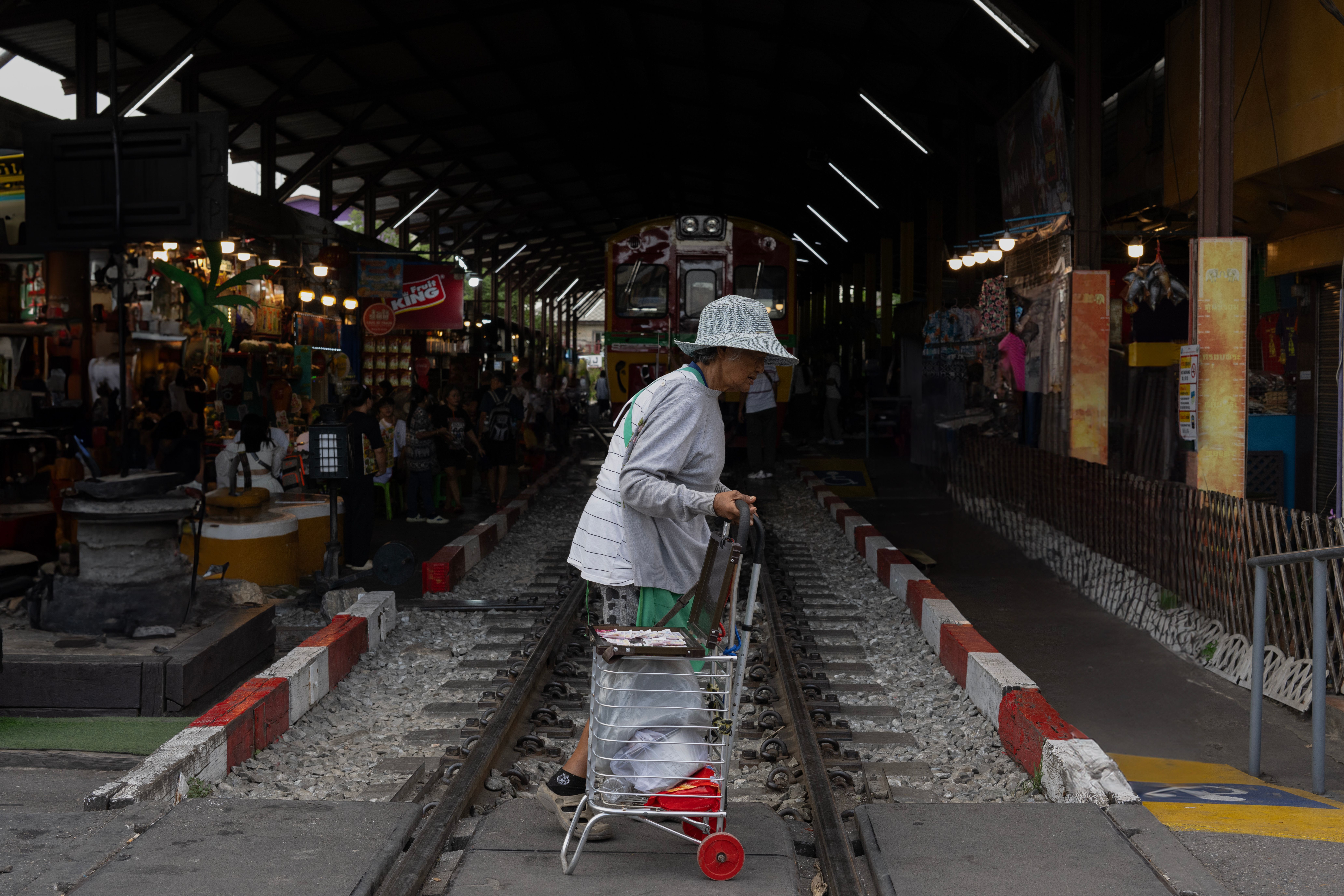 Elderly Woman Crossing Train Tracks in Bangkok Market · Free Stock Photo