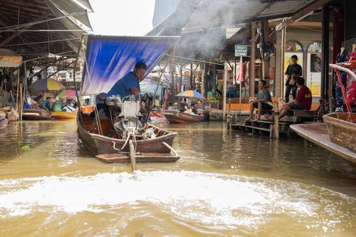 Free Bustling scene of a traditional floating market in Bangkok with boats and local vendors. Stock Photo