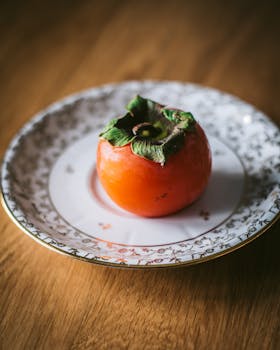 A fresh persimmon elegantly displayed on a vintage plate, evoking autumn vibes.