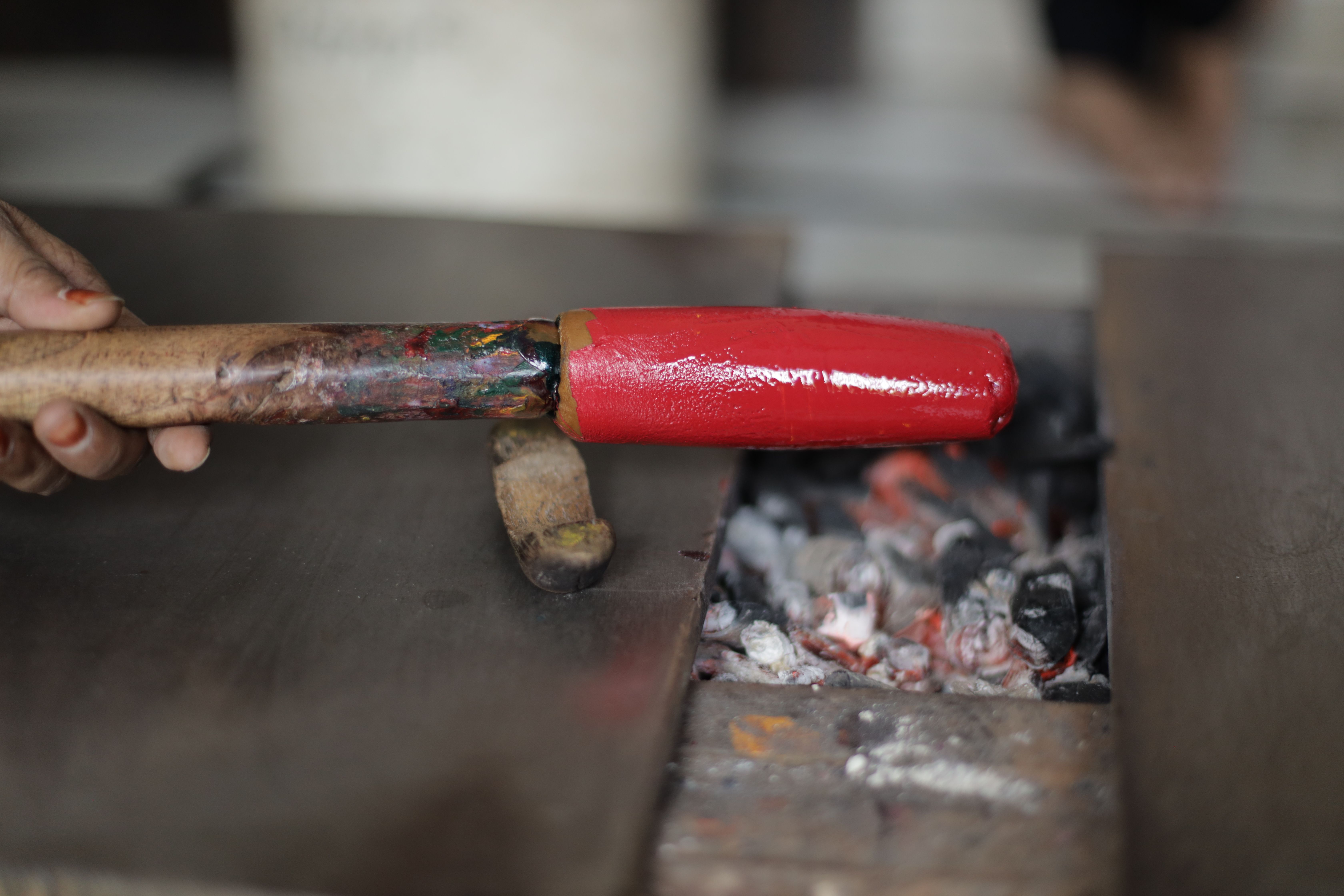 Close-up of a red hot iron tool being heated over charcoal for metalwork.