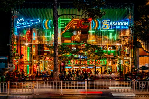 Neon-lit Saigon street scene bustling with activity at night.