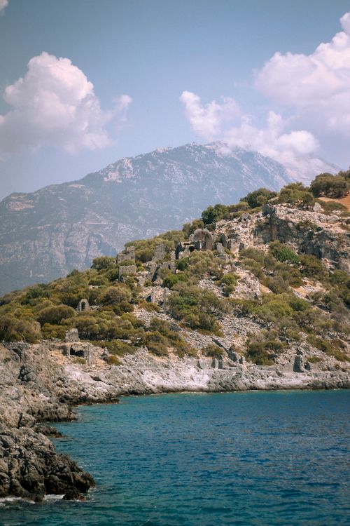 Free Stunning coastal view of ancient ruins against a mountainous backdrop. Stock Photo