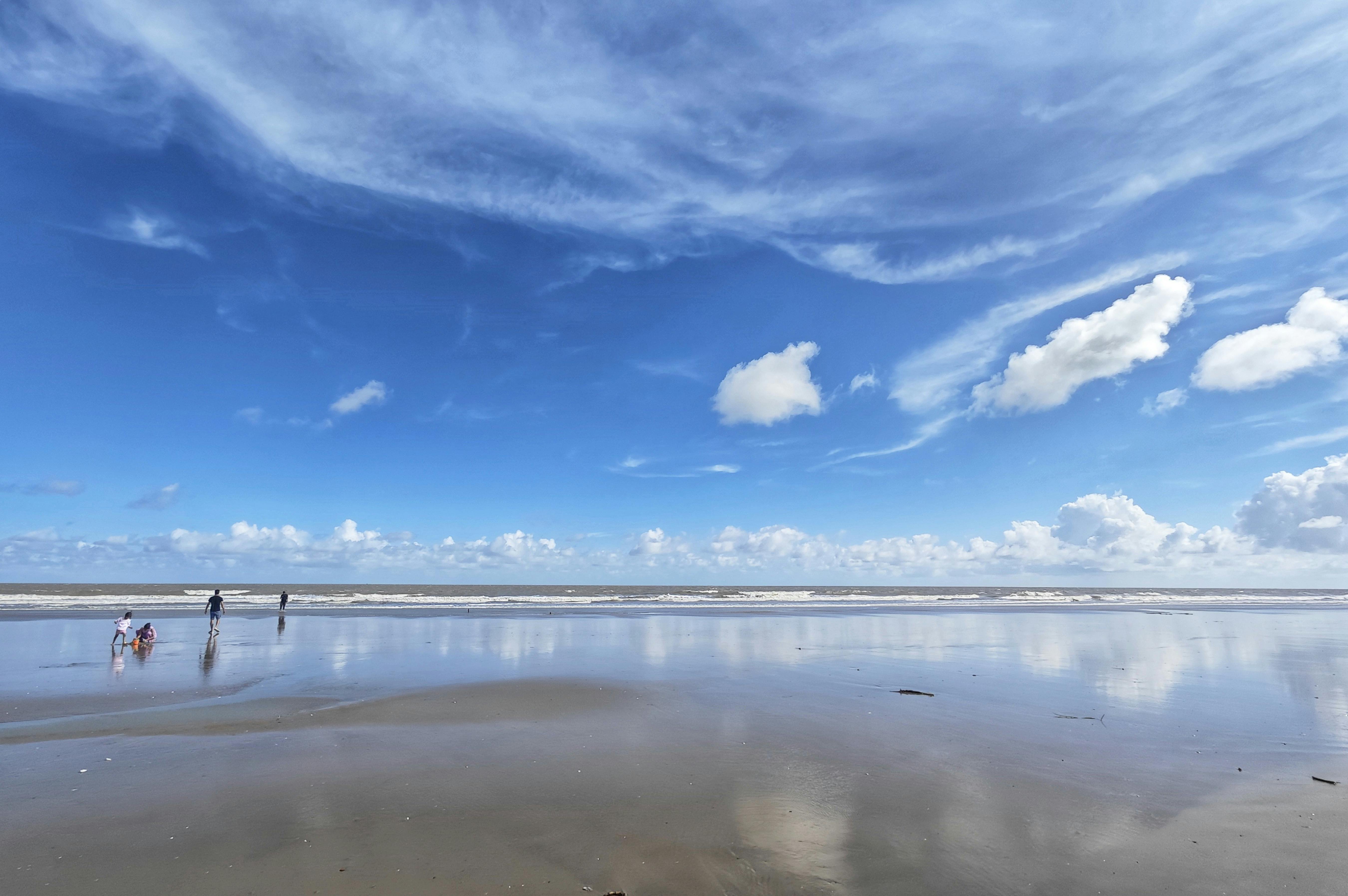 Tranquil beach scene in Mandarmani with a vast blue sky and calm waves.
