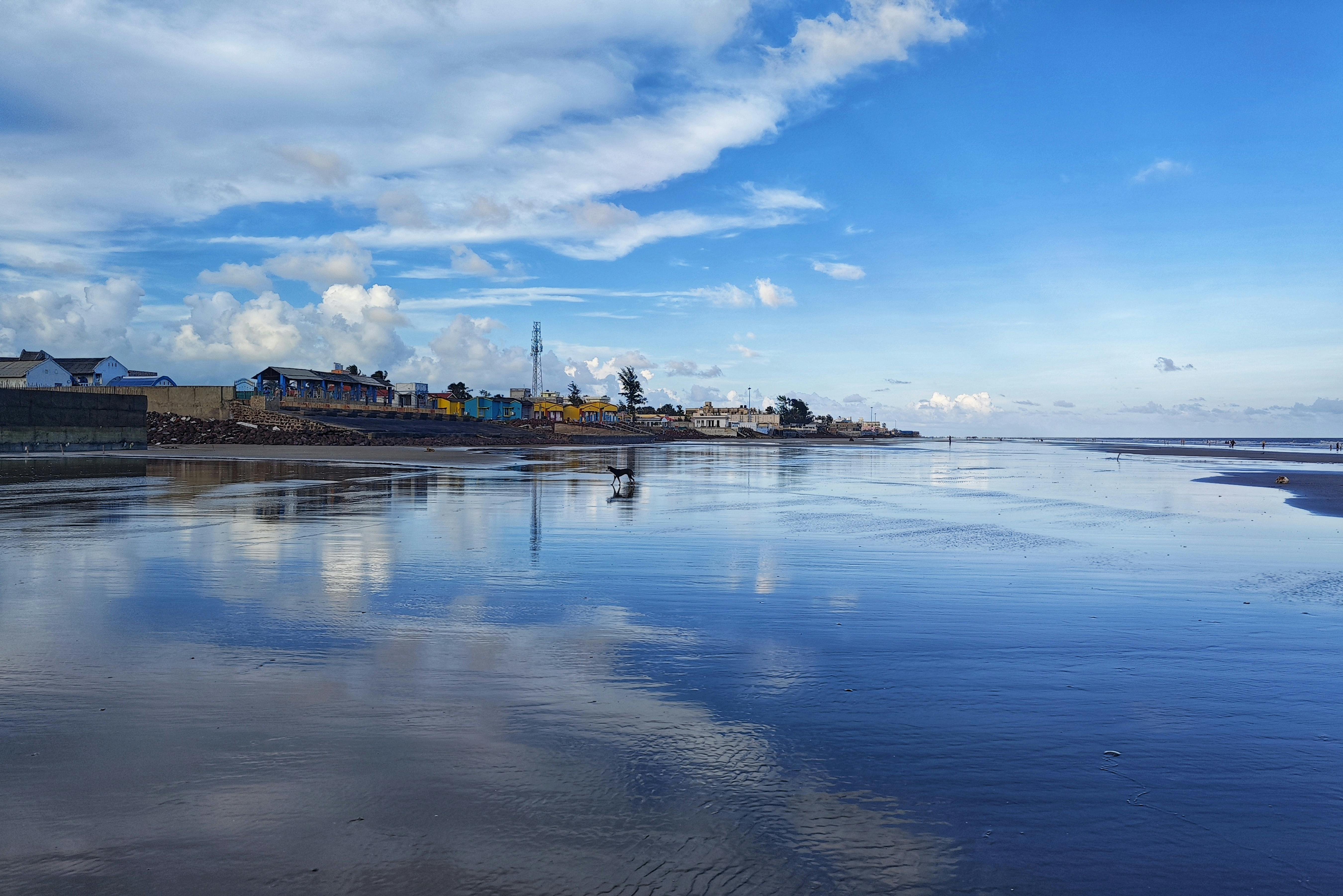 Peaceful beach with vibrant sky reflections in Mandarmani, India.