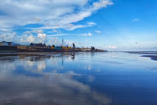 Peaceful beach with vibrant sky reflections in Mandarmani, India.