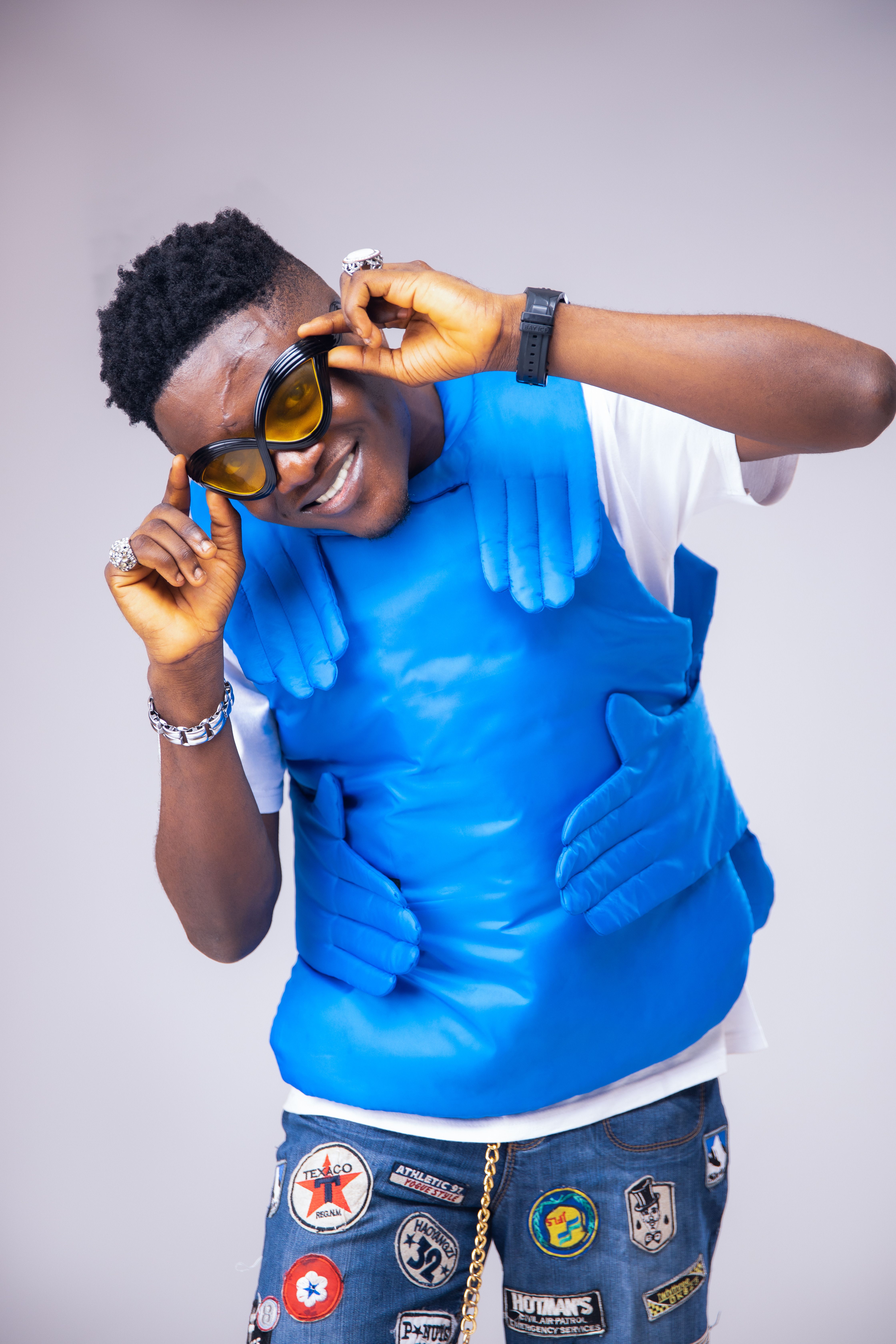 Trendy young adult showcasing unique style with a blue vest and stylish patches.