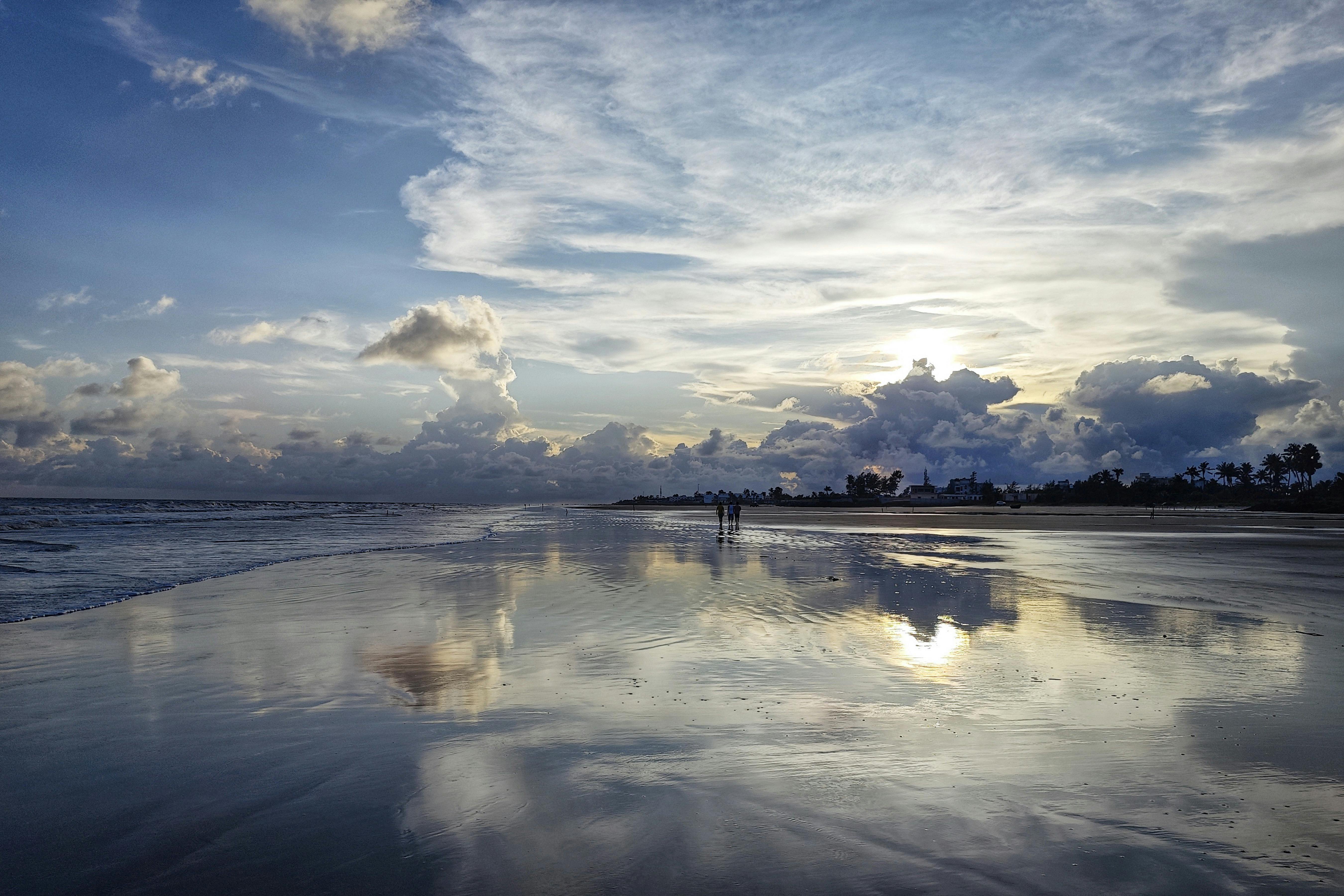 Serene beach landscape in Mandarmani, India, with stunning sunset reflections on the water.