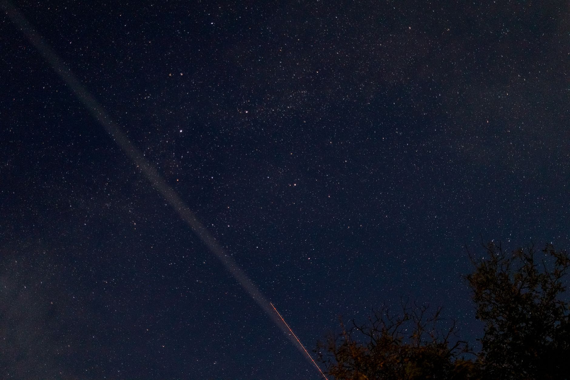 A breathtaking view of a starry night sky with a visible meteor streaking across, captured outdoors.