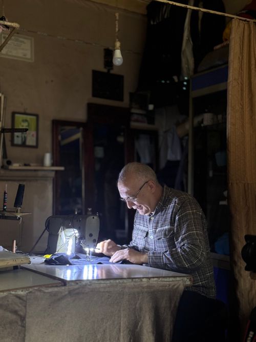Free Elderly man using sewing machine indoors, focused on tailoring work. Stock Photo