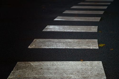 Free Detailed view of a pedestrian crosswalk on a textured asphalt road, ideal for urban themes. Stock Photo