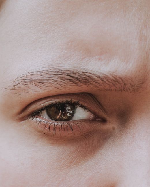 Detailed macro shot of a human eye focusing on the iris, eyelashes, and eyebrow.