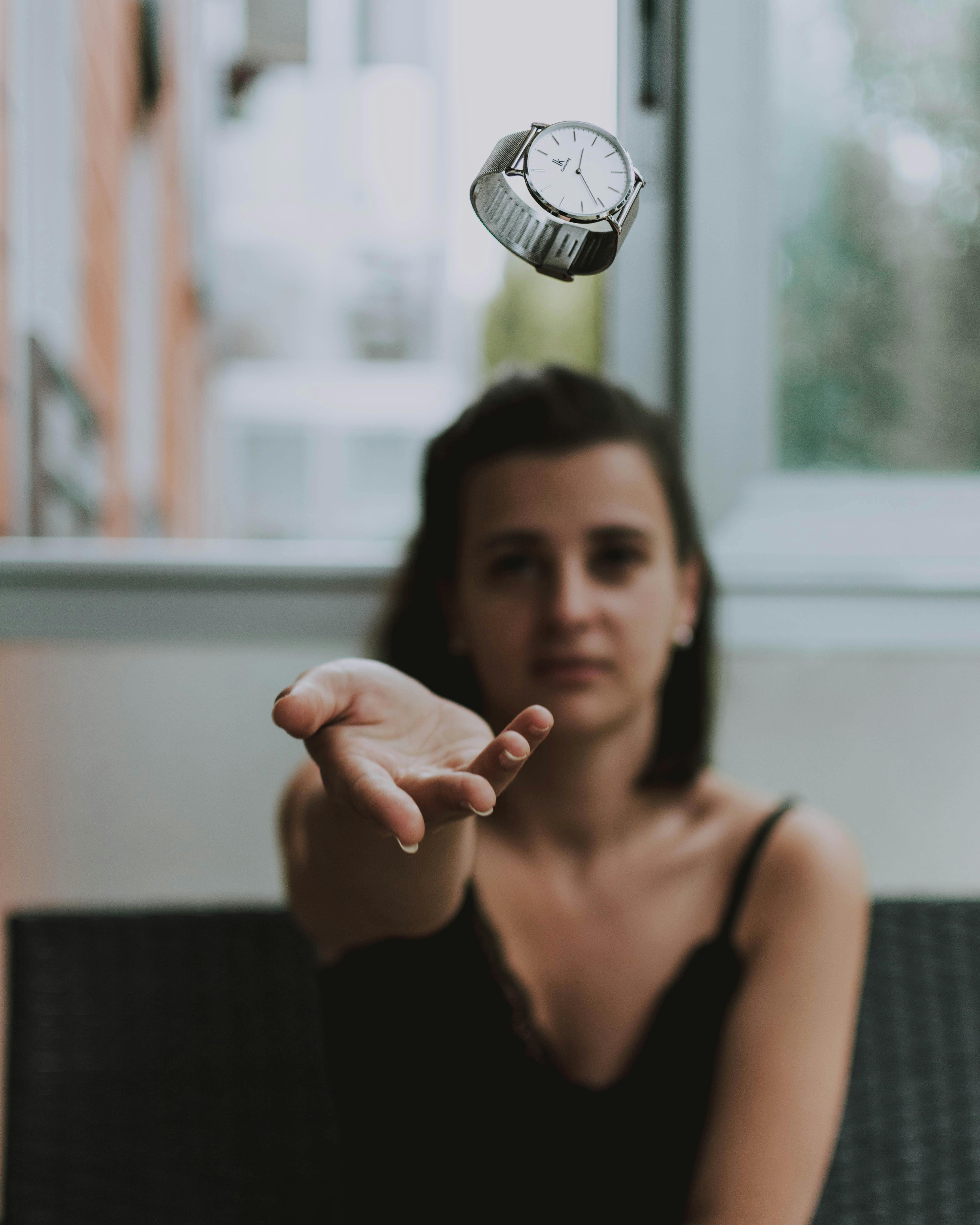 shallow focus photo of person throwing round silver colored analog watch with link bracelet