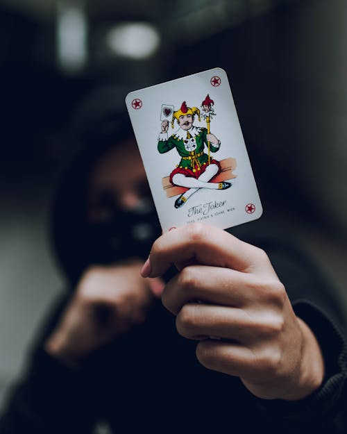 Free Selective Focus Photo of Person Holding Joker Playing Card Stock Photo