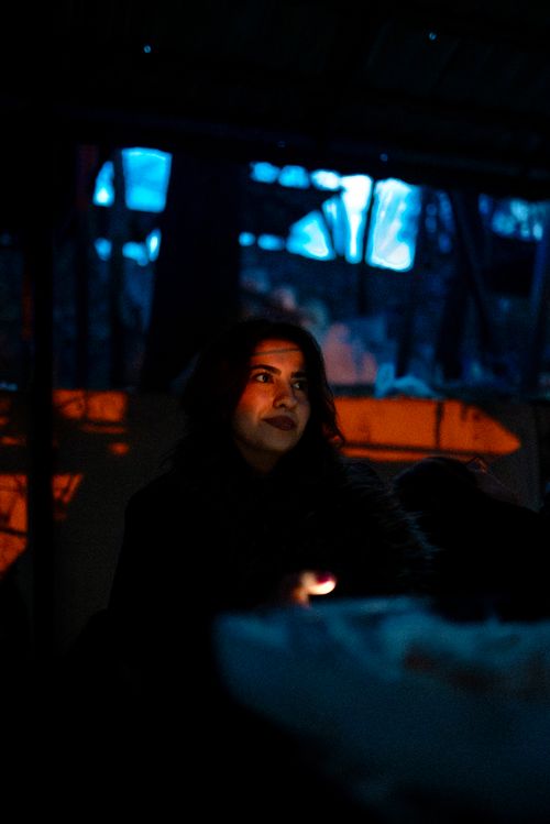 Free Artistic portrait of a woman in dimly lit, moody setting with orange and blue hues. Stock Photo