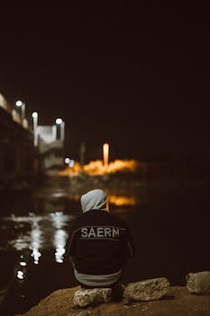 A solitary figure sits by the Nile River at night, capturing a serene moment in Cairo, Egypt.