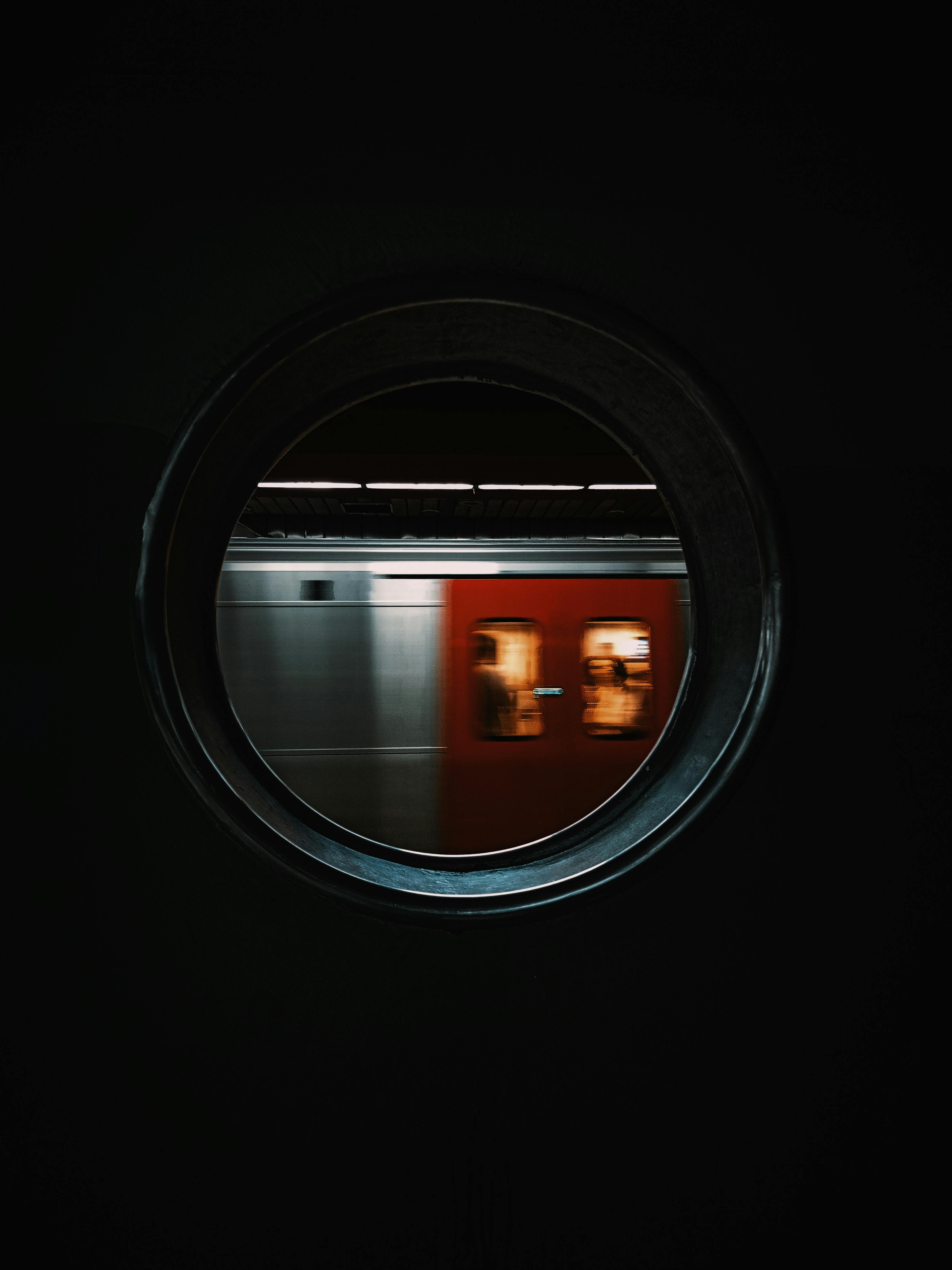 A subway train captured in motion through a circular window, creating a unique frame.
