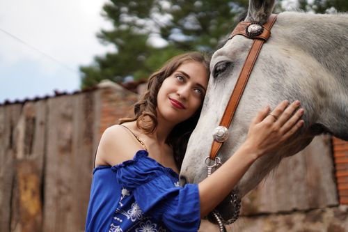 Free A woman lovingly embraces a horse in a rustic outdoor setting, showcasing a connection with nature. Stock Photo