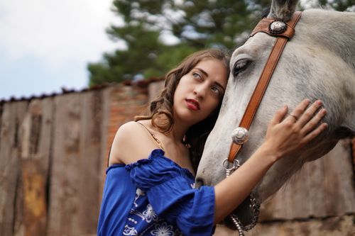 Free Woman in blue embraces horse in an outdoor rustic setting, emotive and serene. Stock Photo