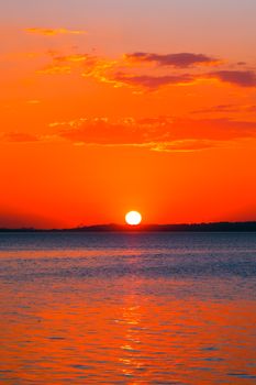 Stunning sunset over the ocean with vibrant hues and serene reflection on water surface.