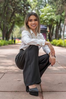 Fashionable Latina woman smiling confidently outdoors in Ciudad de México park.