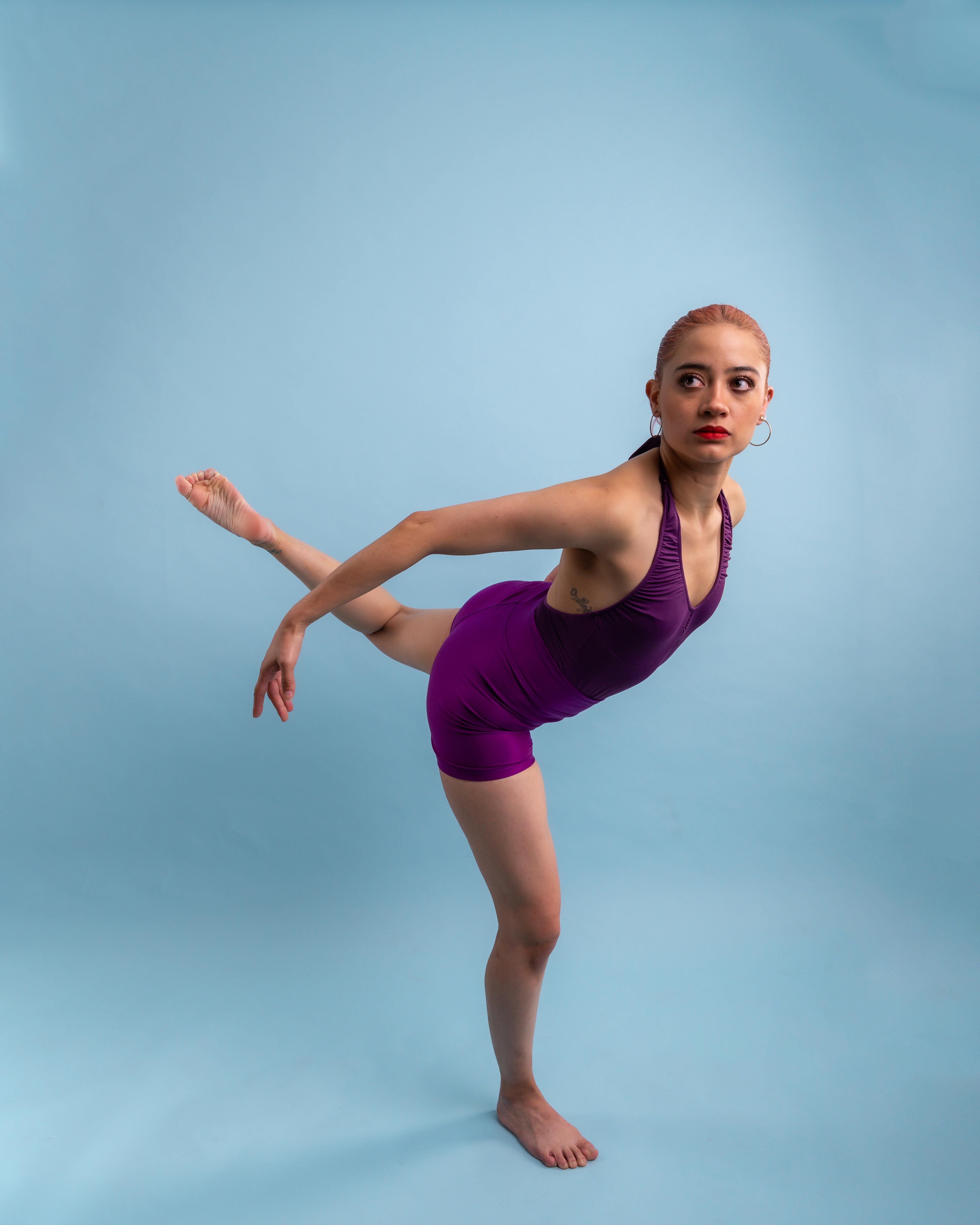 A focused ballerina in a graceful pose against a soft blue background.