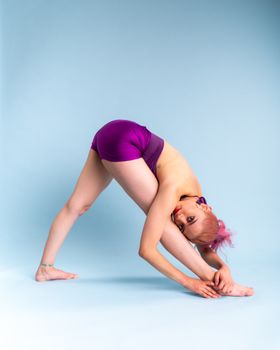 A dancer showcases flexibility and strength with an elegant pose against a light blue background.