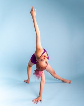 Vibrant dancer striking a creative pose against a soft blue backdrop.