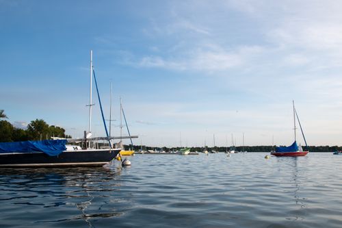 Free Peaceful scene of sailboats docked on a calm lake under a clear sky. Stock Photo