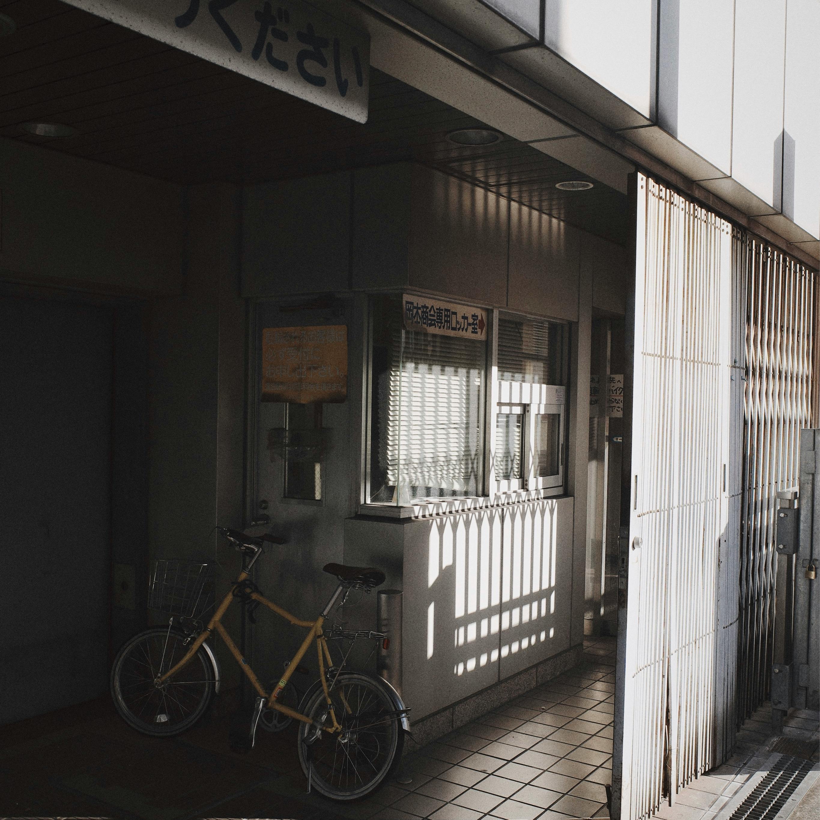 A quiet urban alleyway features a bicycle and soft shadows in warm sunlight.
