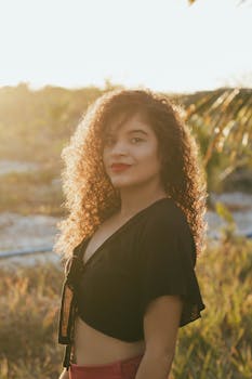 日落时分，一位卷发年轻女子在户外摆姿势