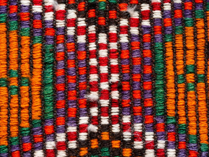 Intricate close-up of a colorful woven textile showcasing vibrant traditional patterns.