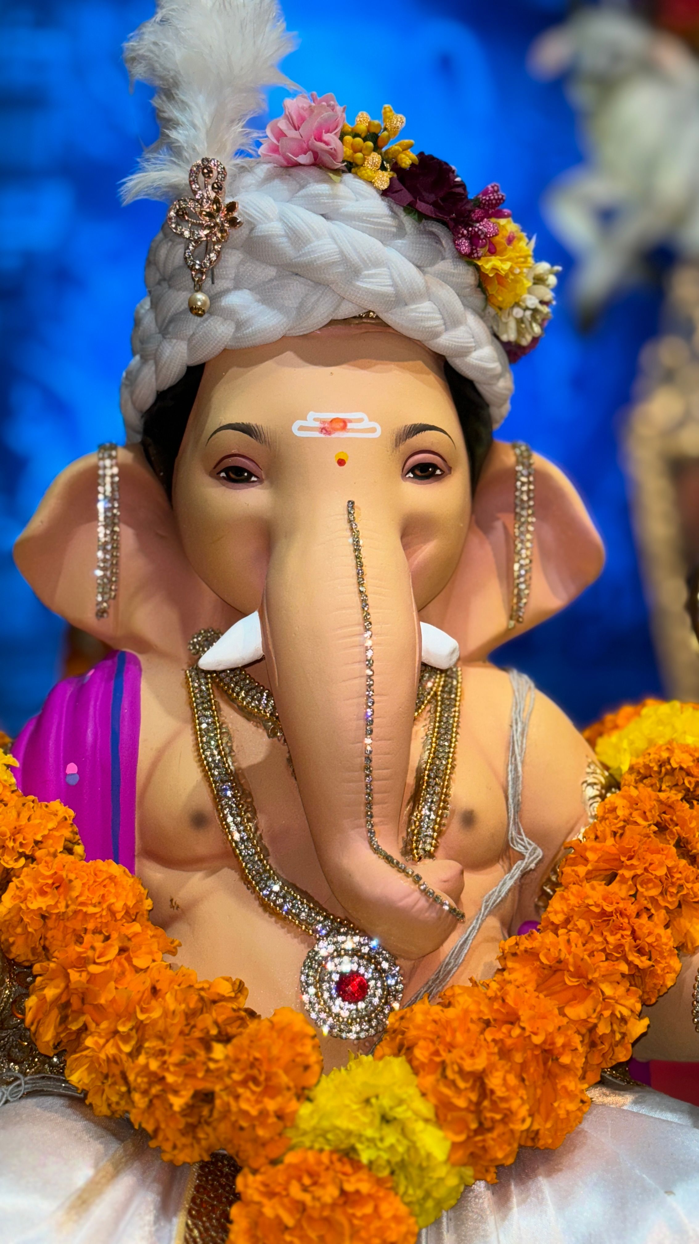 Vibrant Ganesh idol adorned with flowers during festival celebrations.