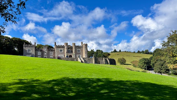 Picturesque Watermouth Castle surrounded by lush green countryside under a clear blue sky in Devon, England.