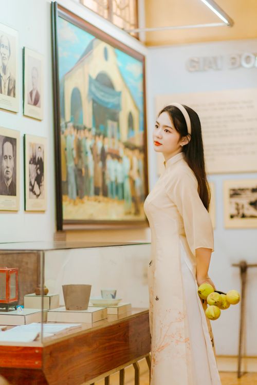 Free A woman in traditional attire examines exhibits in an art gallery, holding green apples. Stock Photo
