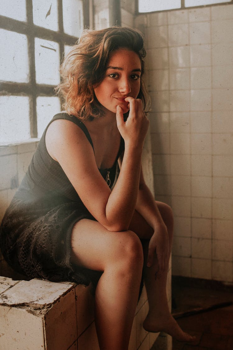 Photo Of Woman In Black Sleeveless Dress Sitting Alone On Tiled Counter