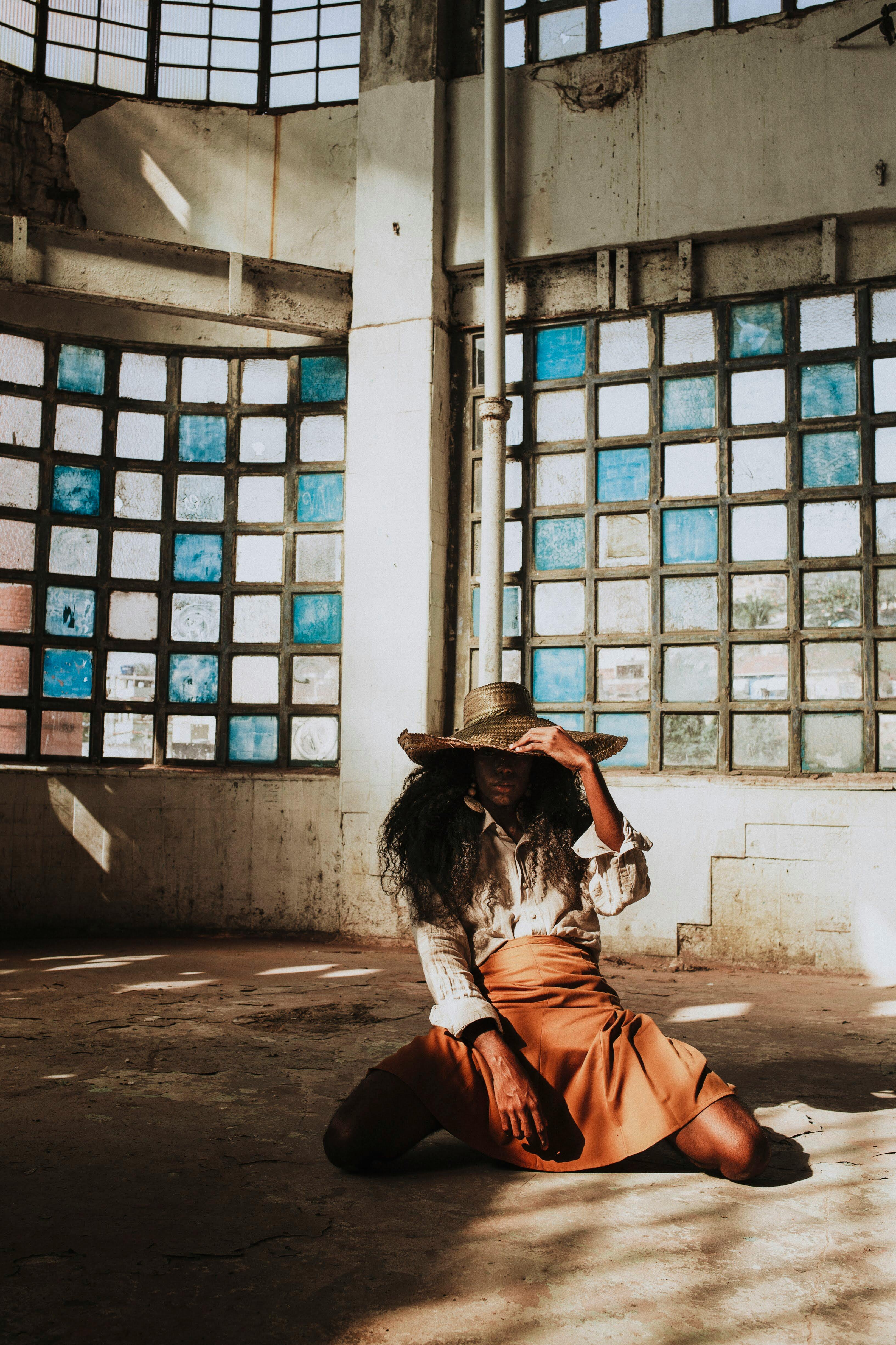 一位时尚女士在阳光明媚的城市室内，戴着帽子摆出优雅的姿势