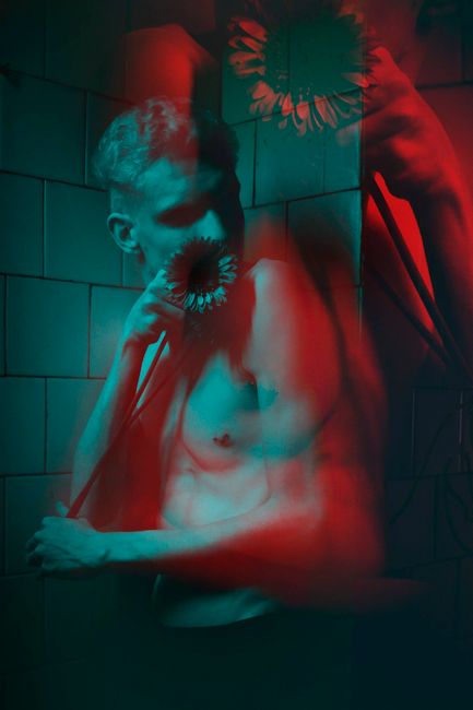 Artistic double exposure of a young man with a flower, moody lighting.