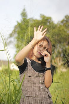 一名年轻女子在阳光明媚的绿色田野中摆姿，享受户外时光