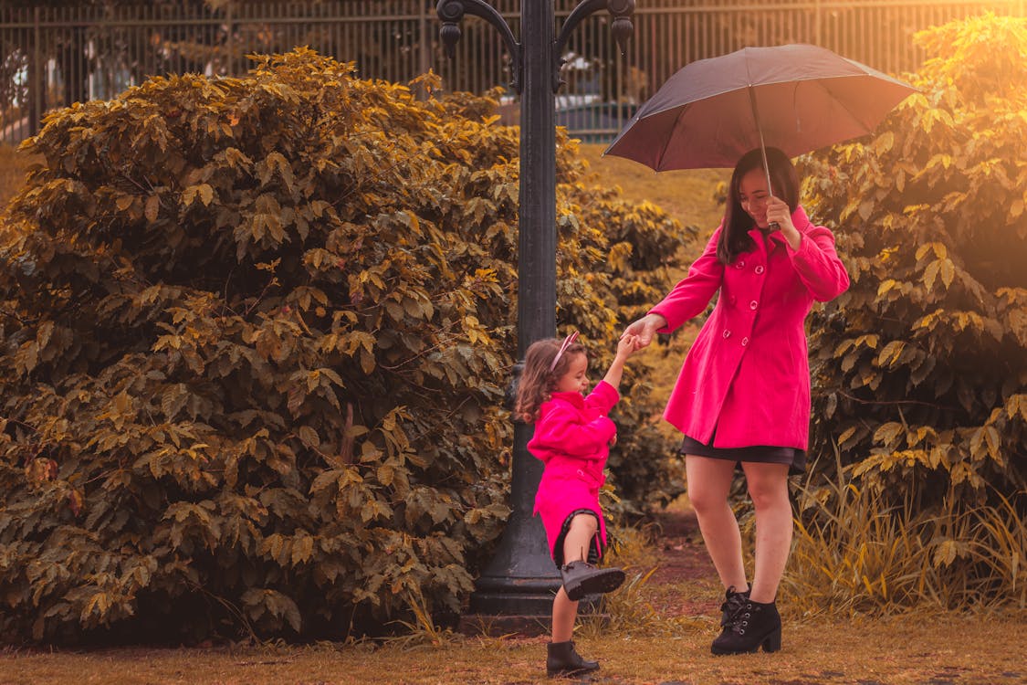 Woman Holding Umbrella While Holding Girl's Hand