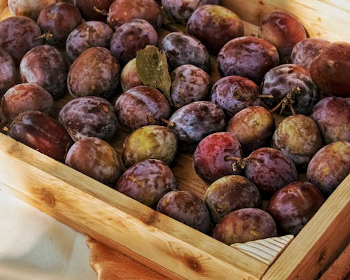 Close-Up Photo of Fresh Plums on a Brown Wooden Crate